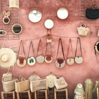 Photo by julie aagaard Aesthetic display of handmade wicker and straw accessories against a textured pink wall.